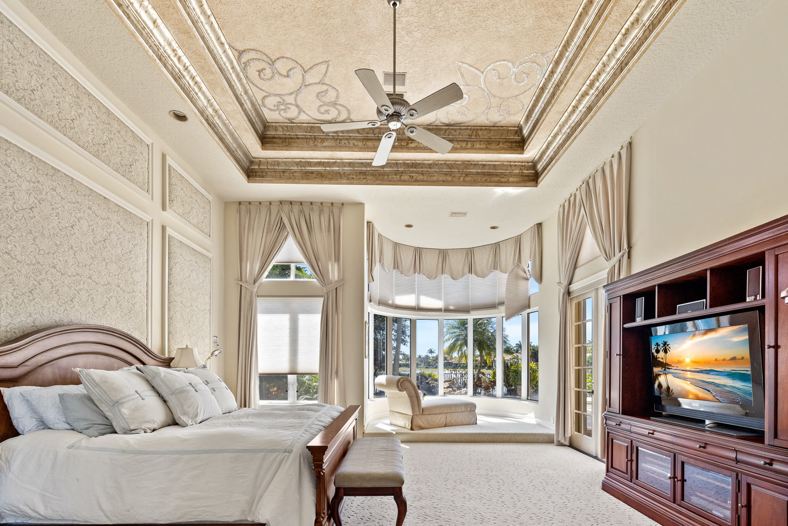 Primary bedroom with tray ceiling and bay window seating area