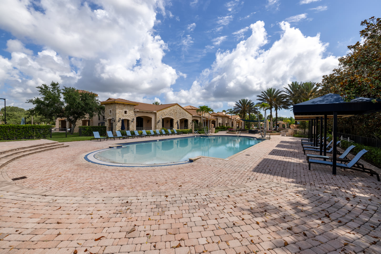 Community clubhouse and pool in daylight with palm trees