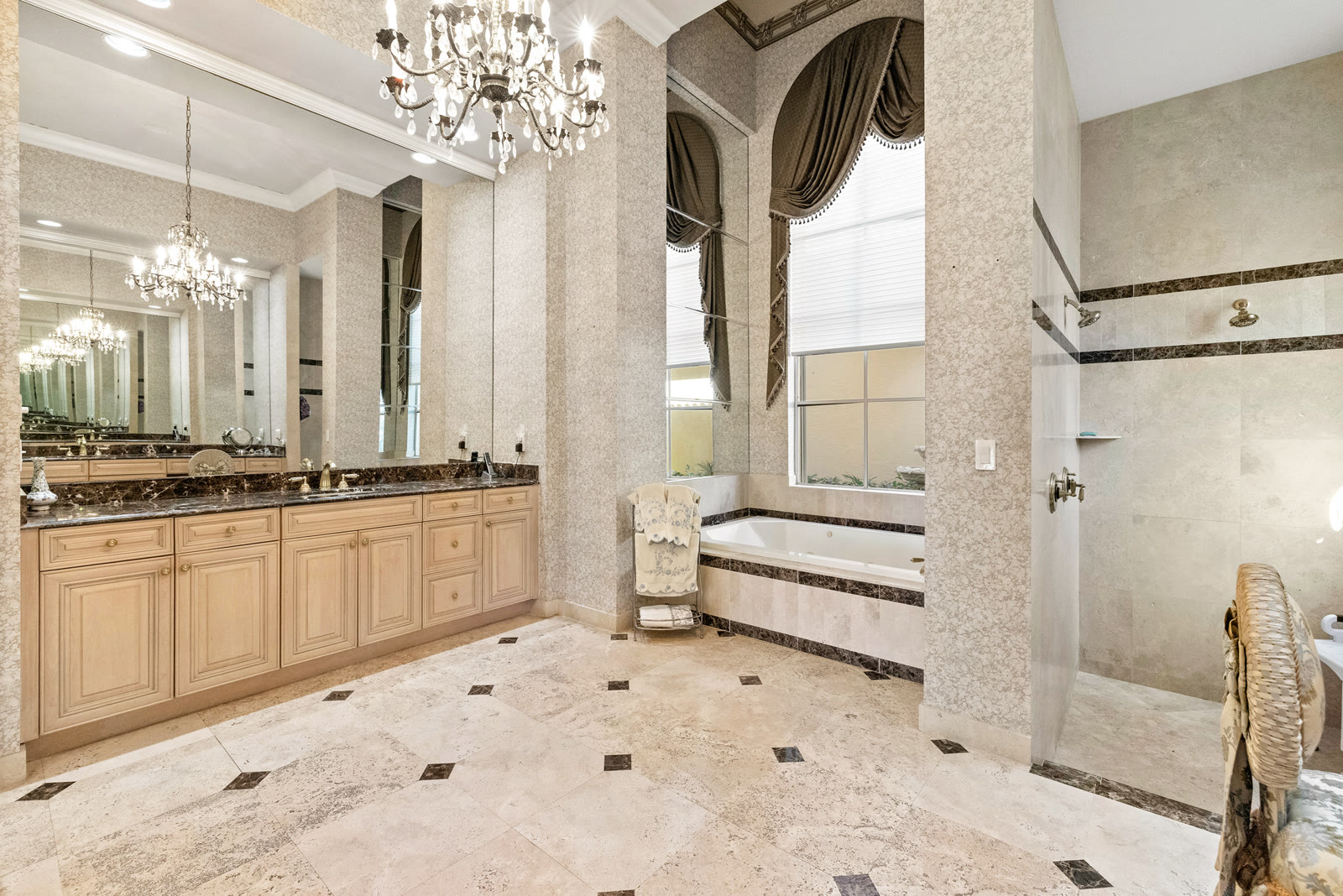 Luxury primary bathroom with crystal chandelier and marble finishes