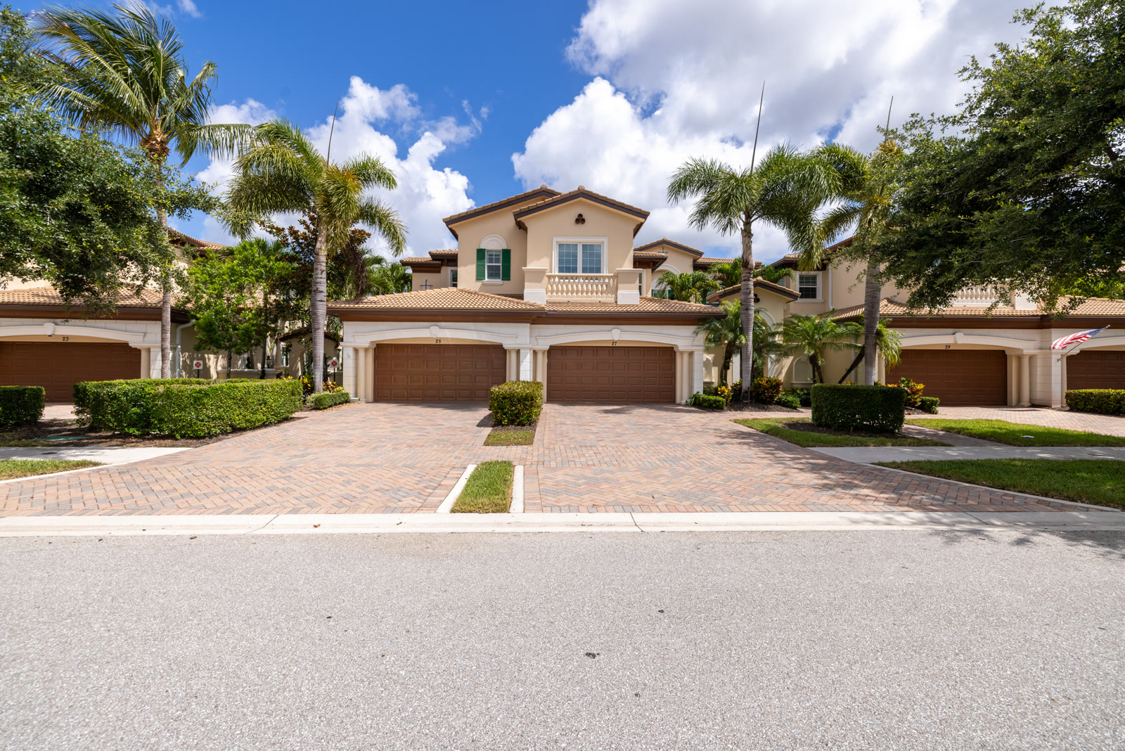 Street view of a Mediterranean-style townhome exterior with palm trees